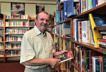 Gerd Lewin beim Blättern in einem Buch in der Schulbibliothek